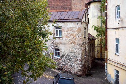 Oldest residential building in Russia, made of stone and brick, behind the green tree - Vyborg, September 2022