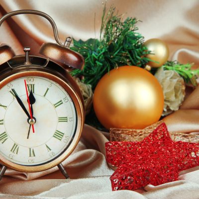 Alarm clock with Christmas decoration on golden cloth background