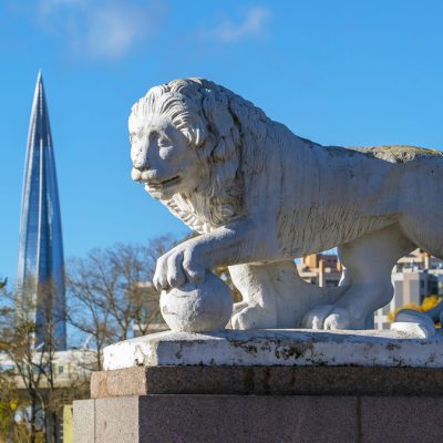 Sculpture of a lion with a ball on the background of the building Lakhta center. Elagin island. Saint Petersburg.